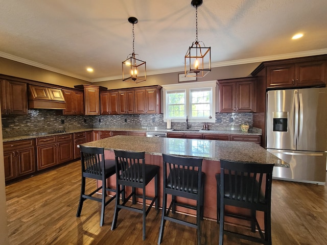 kitchen featuring dark wood-type flooring, appliances with stainless steel finishes, a center island, and ornamental molding