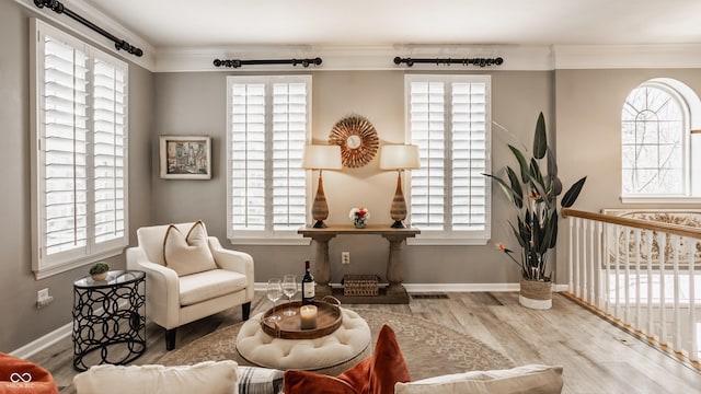 living area with a wealth of natural light, visible vents, wood finished floors, and crown molding