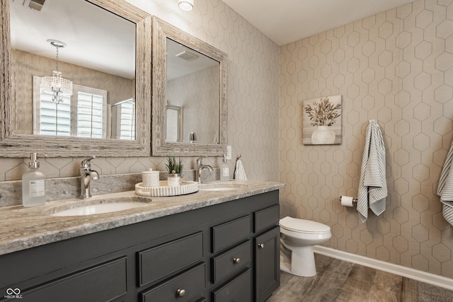 full bathroom featuring double vanity, toilet, wood finished floors, and a sink