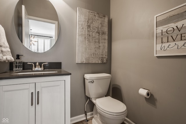 bathroom featuring toilet, vanity, and baseboards