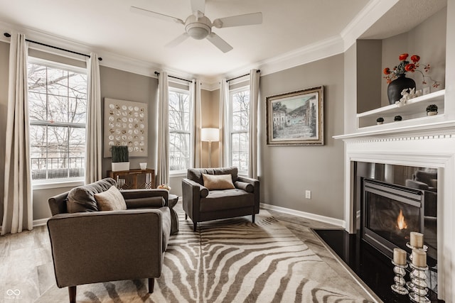 sitting room with crown molding, plenty of natural light, a ceiling fan, and baseboards