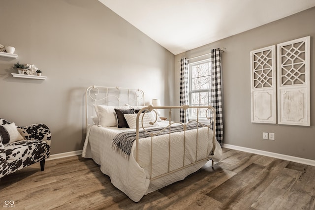 bedroom with baseboards, lofted ceiling, and wood finished floors