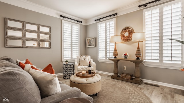 living area with visible vents, a healthy amount of sunlight, wood finished floors, and ornamental molding