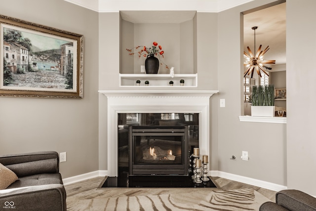 living area featuring a fireplace with flush hearth, baseboards, and wood finished floors