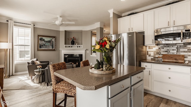 kitchen featuring a glass covered fireplace, dark countertops, crown molding, and stainless steel appliances