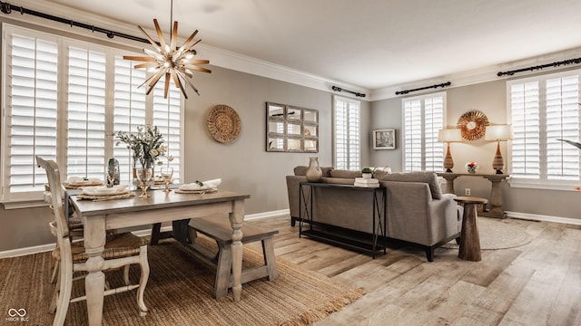 living area with ornamental molding, baseboards, light wood finished floors, and a chandelier