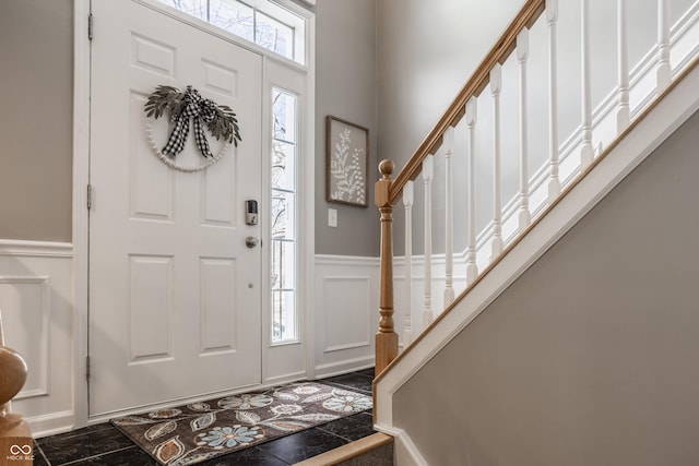 entrance foyer with a wainscoted wall, stairway, and a decorative wall