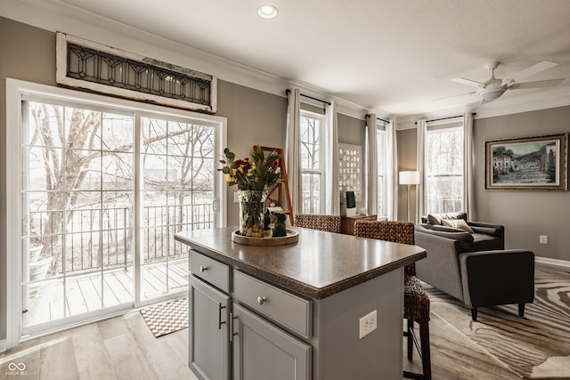 kitchen featuring dark countertops, a kitchen island, a breakfast bar, crown molding, and open floor plan