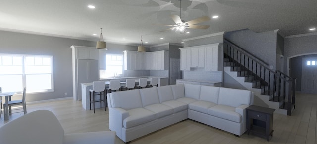 living room featuring ceiling fan, ornamental molding, and light hardwood / wood-style floors