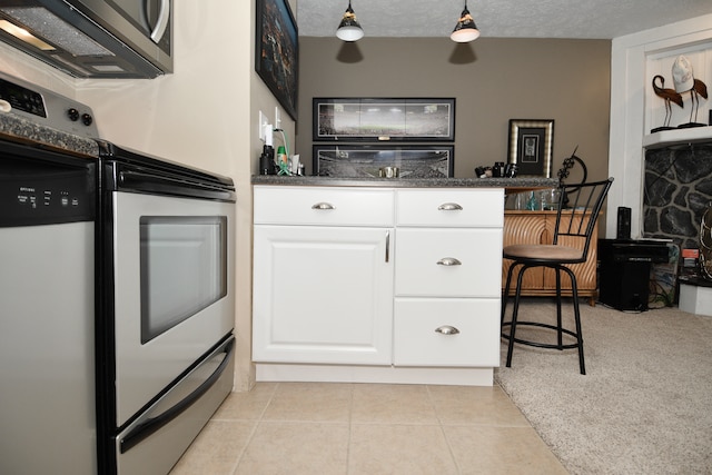 kitchen with stainless steel electric range, white cabinets, decorative light fixtures, a textured ceiling, and light tile patterned flooring