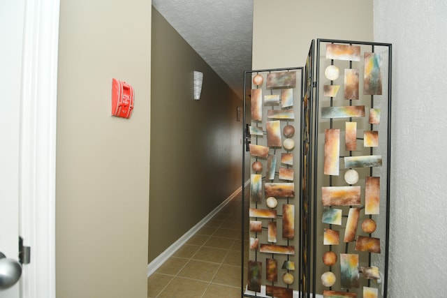 corridor featuring a textured ceiling and tile patterned floors