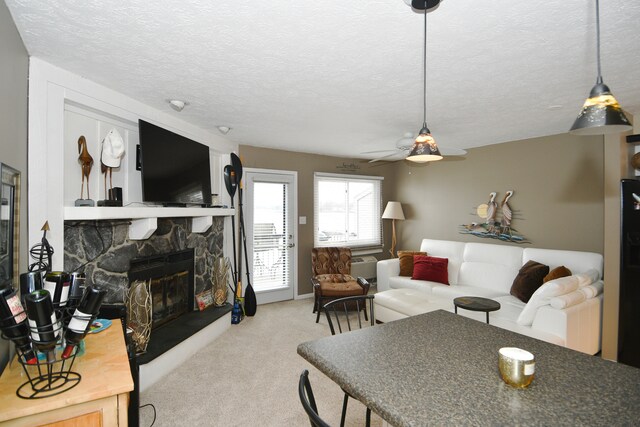 living room with a stone fireplace, light carpet, a textured ceiling, and ceiling fan