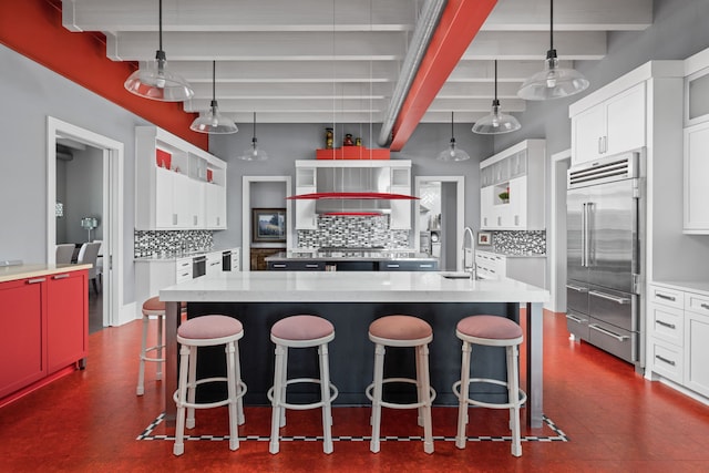 kitchen featuring built in fridge, a breakfast bar, a sink, and a spacious island