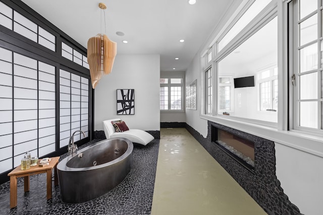 full bath with recessed lighting, a fireplace, baseboards, finished concrete flooring, and a jetted tub