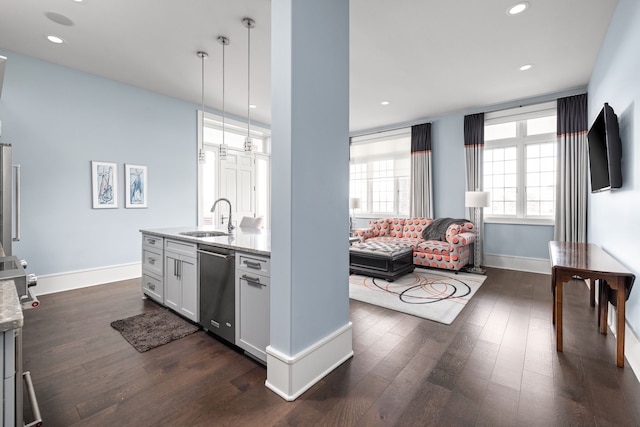 kitchen featuring stainless steel dishwasher, dark wood-type flooring, a sink, light stone countertops, and baseboards