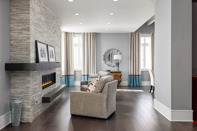 living area featuring dark wood-style floors, baseboards, a tiled fireplace, and recessed lighting