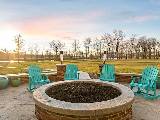 patio terrace at dusk with an outdoor fire pit and a lawn