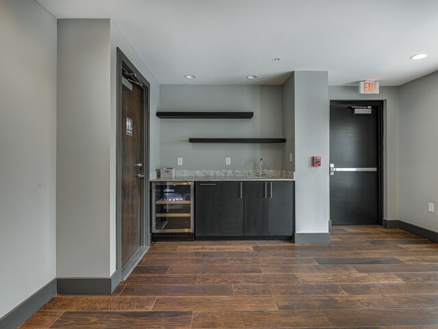 bar with dark brown cabinets, dark hardwood / wood-style floors, wine cooler, and sink