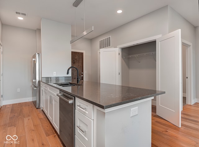 kitchen featuring dark stone counters, sink, light wood-type flooring, white cabinetry, and stainless steel appliances