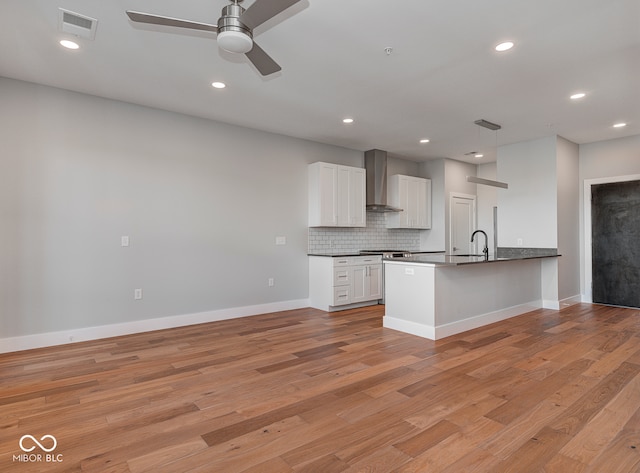 kitchen with white cabinets, backsplash, light hardwood / wood-style floors, and wall chimney exhaust hood