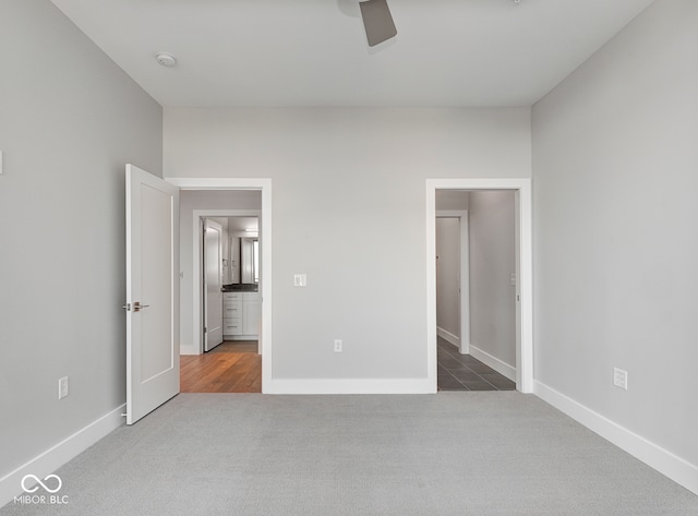 unfurnished bedroom with dark colored carpet and ceiling fan