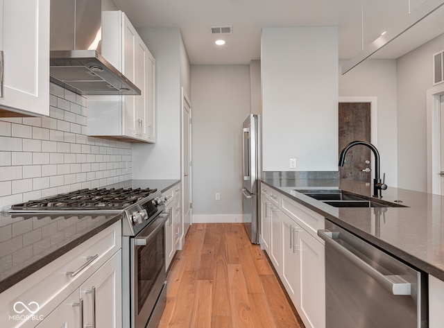 kitchen featuring sink, wall chimney range hood, light hardwood / wood-style flooring, high quality appliances, and white cabinets