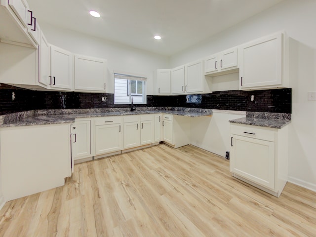 kitchen with decorative backsplash, light hardwood / wood-style flooring, and white cabinetry