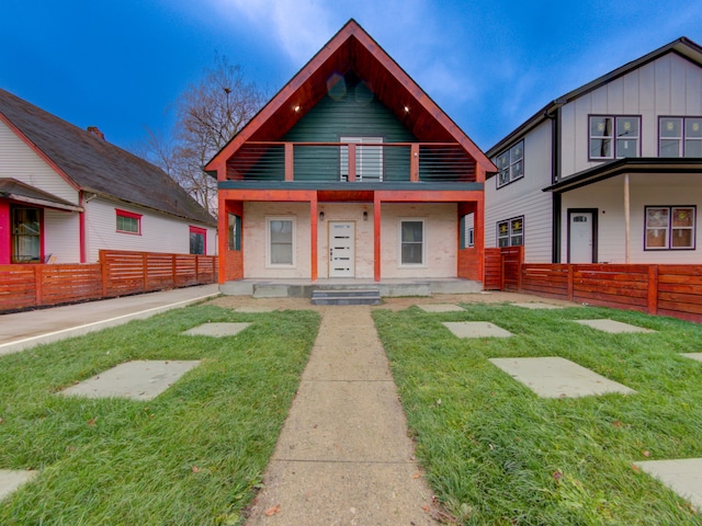 view of front of house featuring a balcony and a front lawn