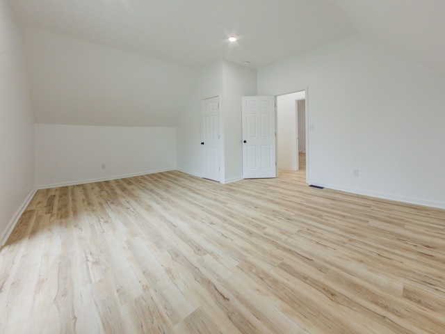 additional living space with light wood-type flooring and vaulted ceiling