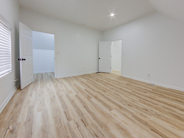 unfurnished bedroom with light hardwood / wood-style flooring and lofted ceiling