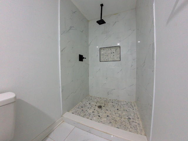 bathroom featuring tiled shower, tile patterned flooring, and toilet