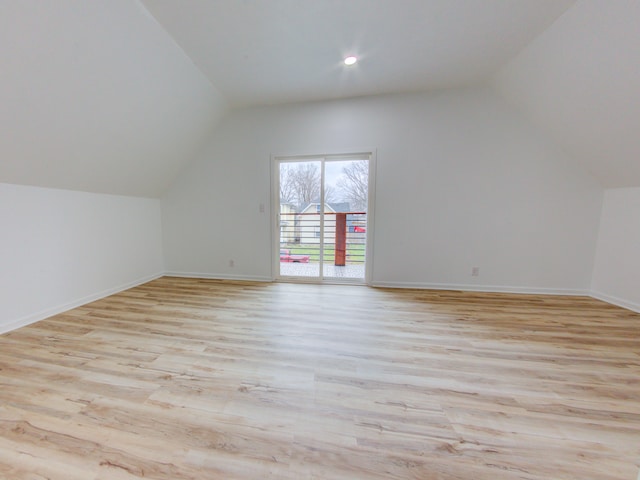 additional living space with light hardwood / wood-style flooring and lofted ceiling