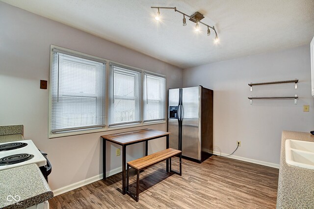 kitchen featuring electric range, baseboards, stainless steel fridge with ice dispenser, light wood-style flooring, and a sink