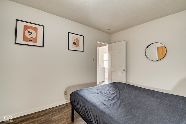 bedroom with a textured ceiling, baseboards, and wood finished floors