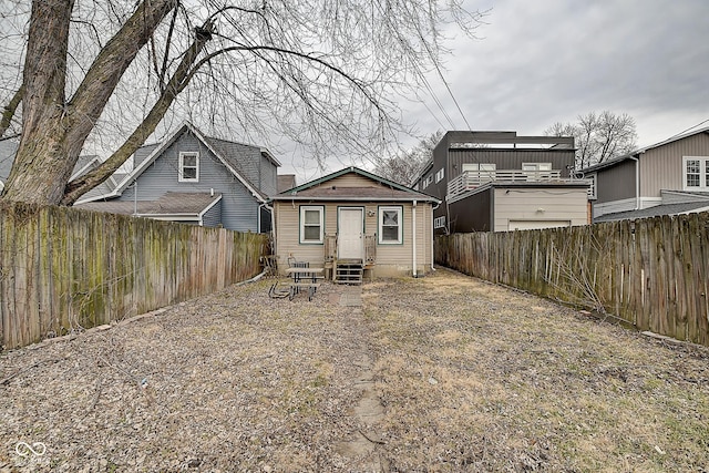 rear view of property featuring entry steps and a fenced backyard