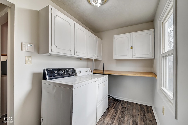 clothes washing area with a textured ceiling, dark wood-style flooring, baseboards, cabinet space, and washing machine and clothes dryer