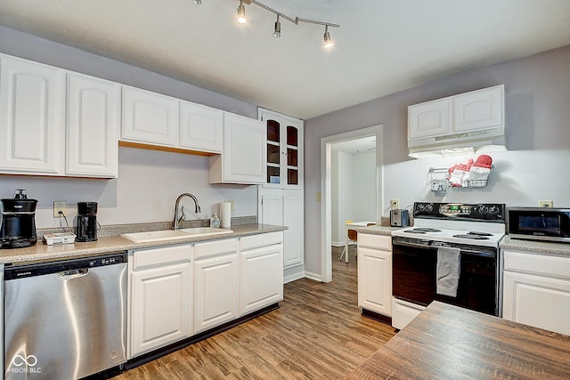 kitchen featuring under cabinet range hood, stainless steel appliances, a sink, white cabinetry, and light wood-type flooring