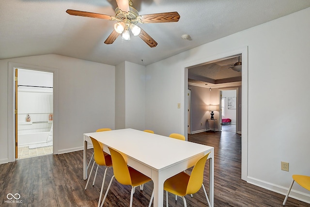 dining room with dark wood-style floors, vaulted ceiling, baseboards, and a ceiling fan