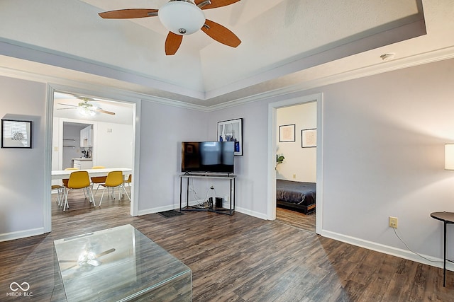 living room with baseboards, ornamental molding, wood finished floors, a tray ceiling, and vaulted ceiling