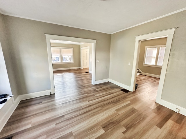 empty room featuring light wood-type flooring and ornamental molding