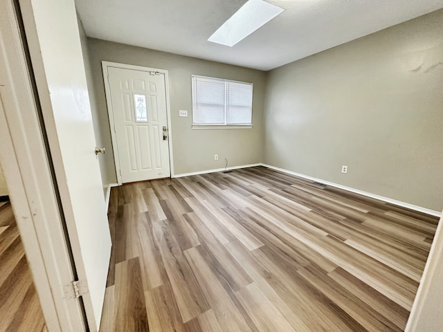 foyer with light hardwood / wood-style flooring and a skylight