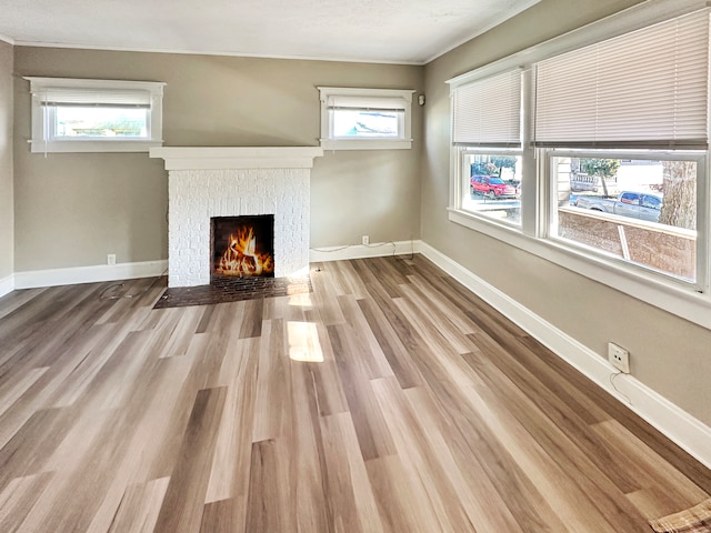 unfurnished living room with a fireplace, ornamental molding, and light hardwood / wood-style flooring