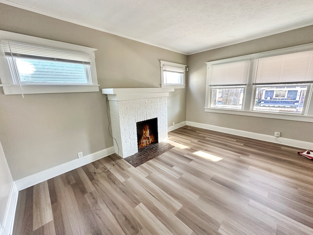 unfurnished living room featuring crown molding, a textured ceiling, and light hardwood / wood-style flooring