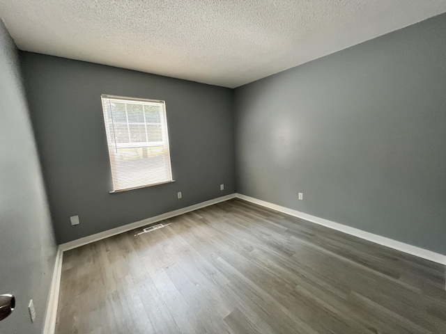 spare room with a textured ceiling and dark hardwood / wood-style flooring