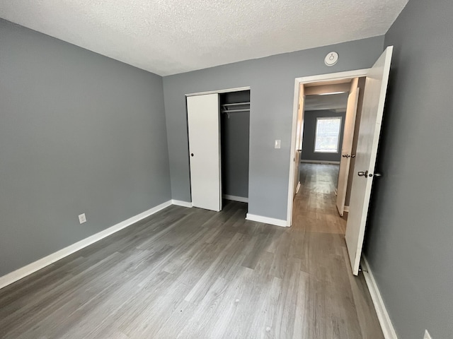 unfurnished bedroom featuring dark wood-type flooring, a textured ceiling, and a closet