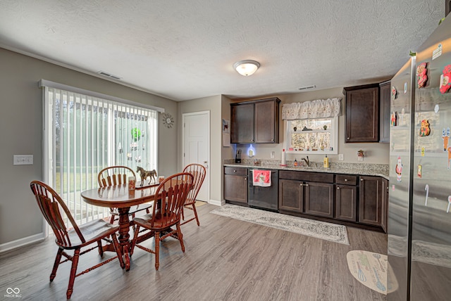 kitchen featuring light wood-type flooring, dark brown cabinets, a textured ceiling, stainless steel appliances, and sink