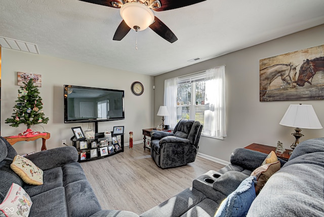 living room with a textured ceiling, light hardwood / wood-style flooring, and ceiling fan