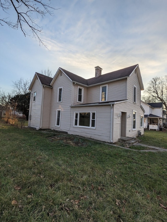 rear view of property with a lawn and a chimney