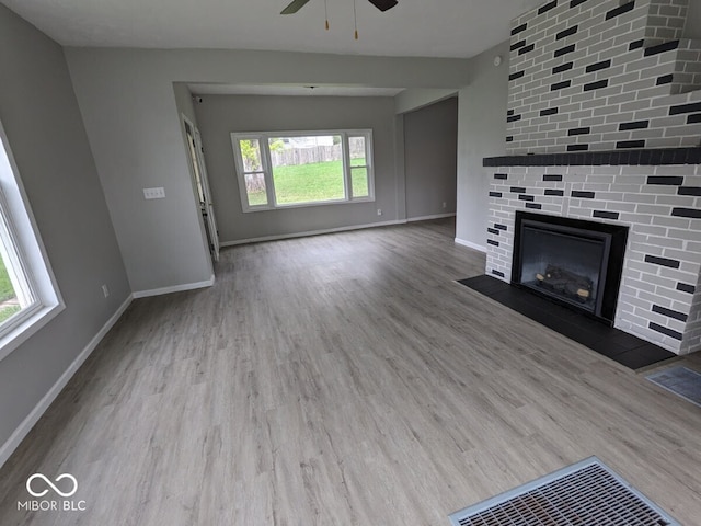 unfurnished living room with a fireplace, hardwood / wood-style floors, ceiling fan, and plenty of natural light