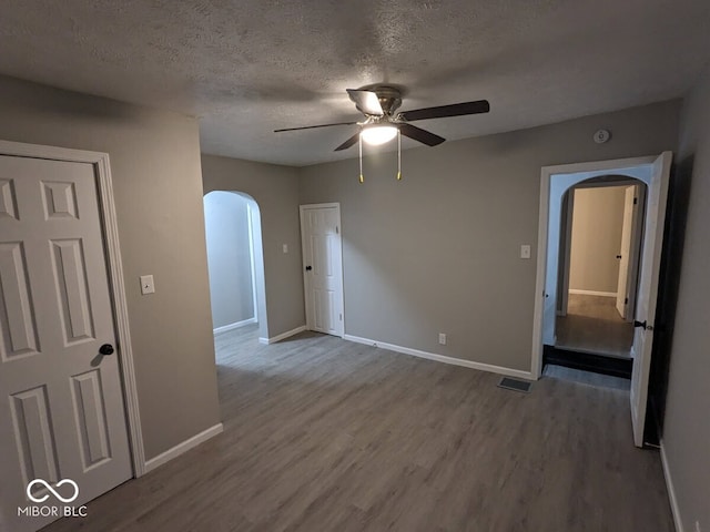 spare room with a textured ceiling, wood-type flooring, and ceiling fan